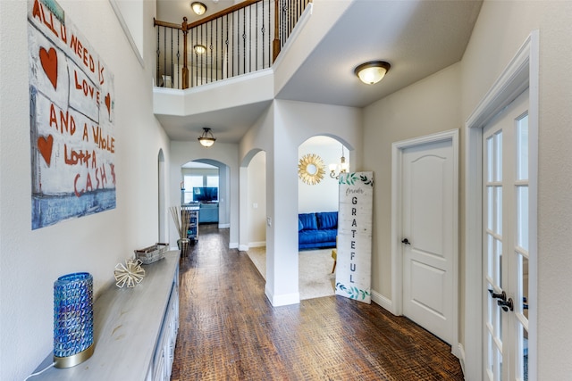 entryway with a towering ceiling and dark wood-type flooring