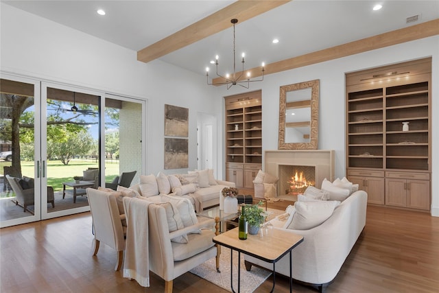 living room featuring dark wood-type flooring, built in features, beamed ceiling, a chandelier, and a fireplace