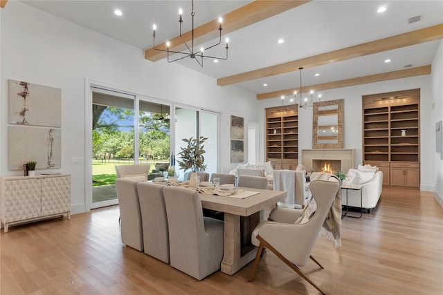 dining space featuring beamed ceiling, light hardwood / wood-style flooring, built in features, and a chandelier