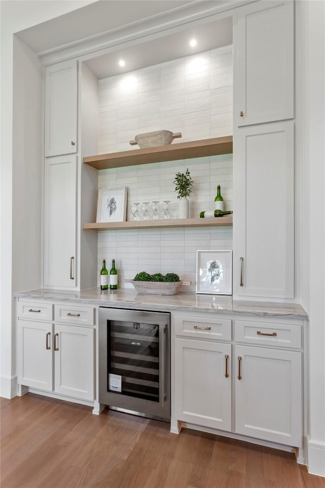 bar featuring backsplash, light hardwood / wood-style flooring, white cabinetry, and beverage cooler