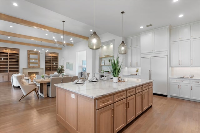 kitchen with paneled fridge, pendant lighting, a center island, and white cabinetry