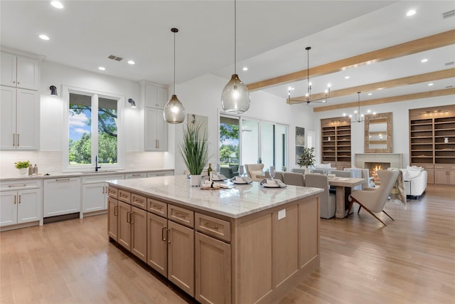 kitchen featuring light stone countertops, white dishwasher, pendant lighting, white cabinets, and a large island