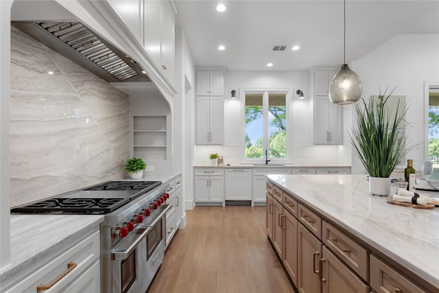 kitchen with white cabinetry, hanging light fixtures, stainless steel stove, and light stone counters