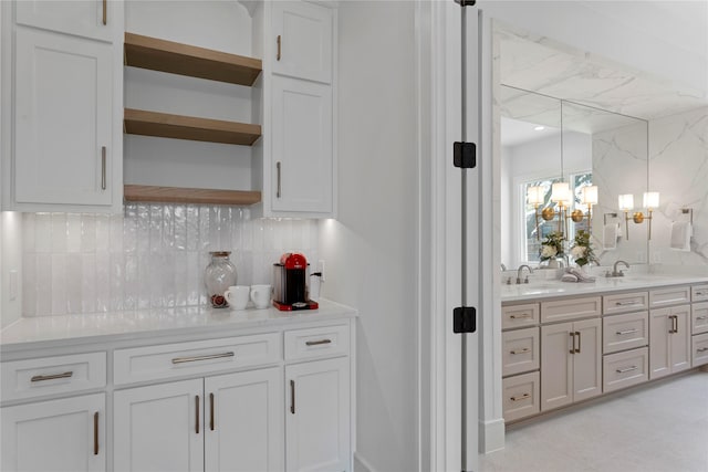 bar with backsplash, white cabinetry, hanging light fixtures, and sink