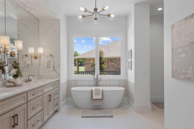 bathroom with a chandelier, tile patterned flooring, vanity, and a bath