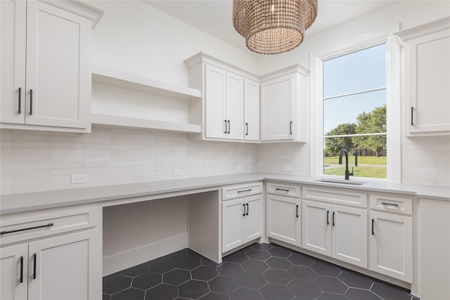 kitchen featuring sink, an inviting chandelier, dark tile patterned floors, decorative backsplash, and white cabinets