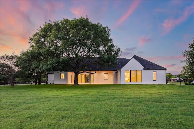 back house at dusk featuring a yard