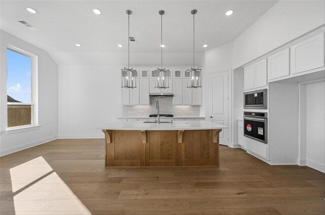 kitchen featuring stainless steel appliances, dark hardwood / wood-style flooring, pendant lighting, a center island with sink, and white cabinets