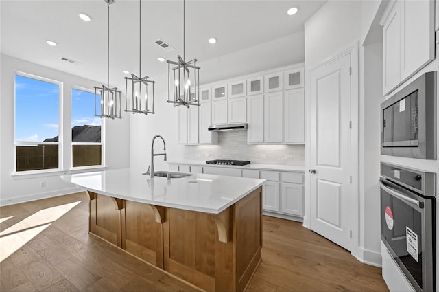 kitchen featuring a kitchen island with sink, sink, white cabinets, and stainless steel appliances