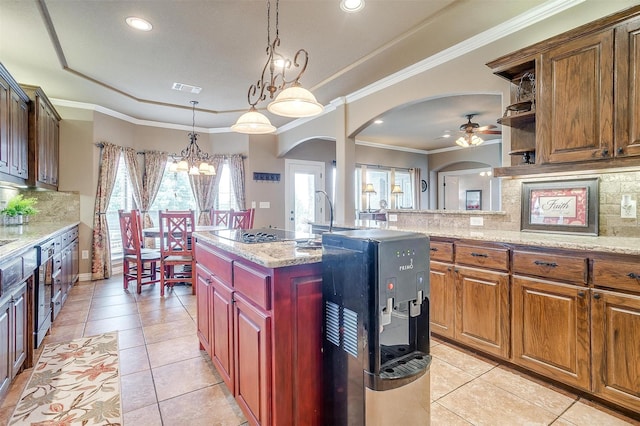 kitchen with light stone counters, visible vents, a center island, decorative light fixtures, and crown molding