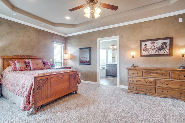 bedroom featuring baseboards, connected bathroom, light colored carpet, a tray ceiling, and crown molding