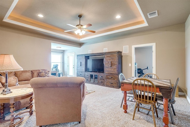 living room featuring carpet flooring, a raised ceiling, visible vents, and a ceiling fan