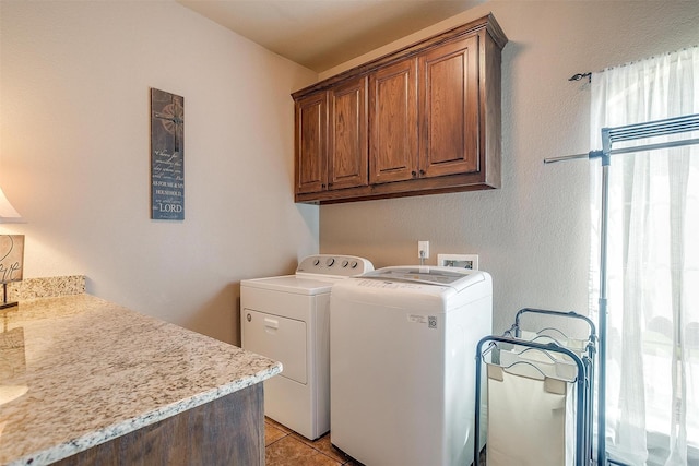 clothes washing area featuring light tile patterned floors, cabinet space, and separate washer and dryer