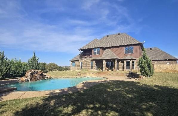 rear view of house featuring an outdoor pool and a yard