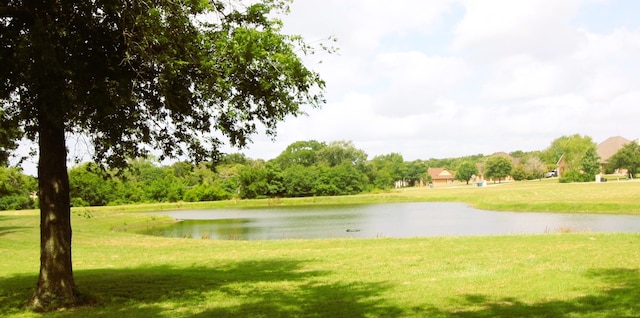 surrounding community with a water view and a lawn