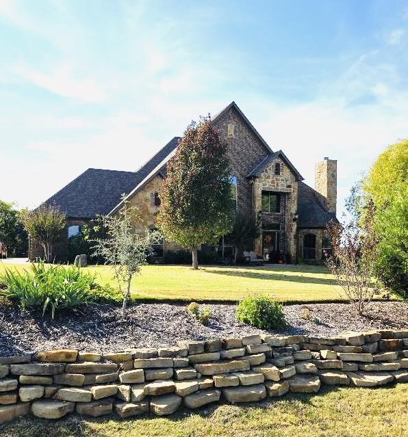 exterior space with stone siding, a lawn, and a chimney