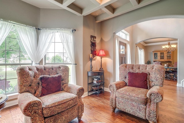 sitting room with arched walkways, a notable chandelier, coffered ceiling, wood finished floors, and baseboards