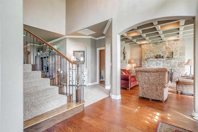 entrance foyer featuring arched walkways, coffered ceiling, wood finished floors, baseboards, and beam ceiling