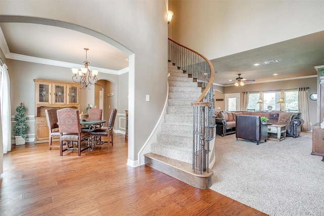 staircase featuring arched walkways, wood finished floors, and ornamental molding