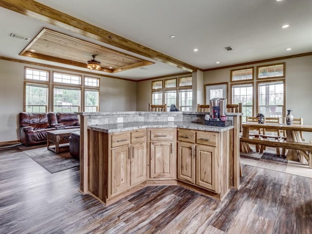 kitchen featuring wood-type flooring, a center island, light stone counters, and ceiling fan