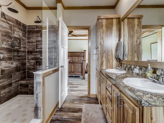 bathroom with tiled shower, hardwood / wood-style floors, vanity, and ornamental molding