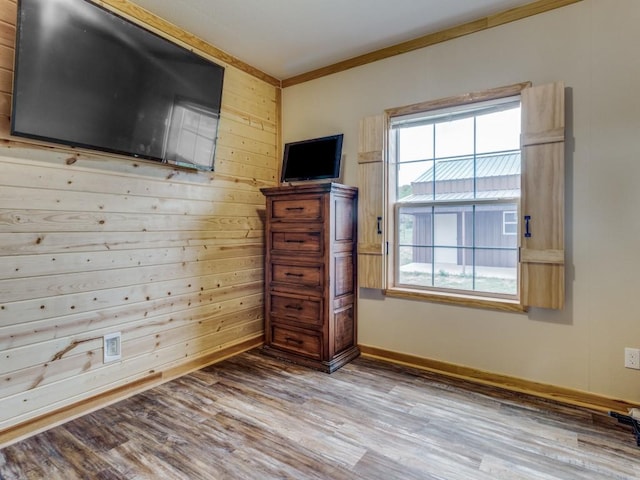 unfurnished bedroom with hardwood / wood-style flooring, crown molding, and wooden walls