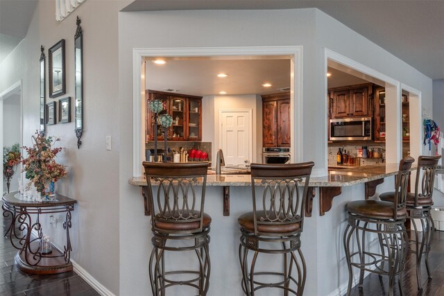 interior space with a kitchen breakfast bar, light stone countertops, and dark hardwood / wood-style floors