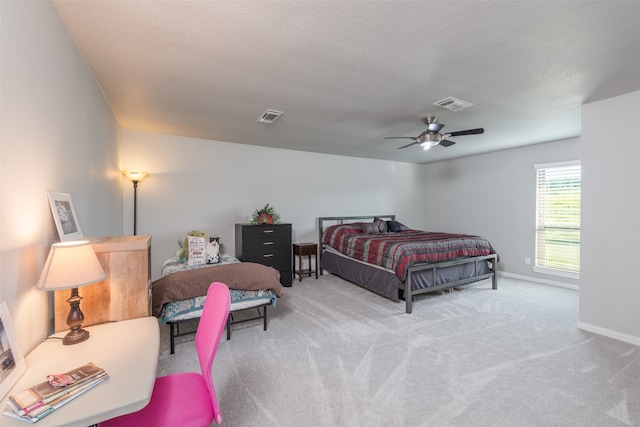 carpeted bedroom featuring ceiling fan and a textured ceiling