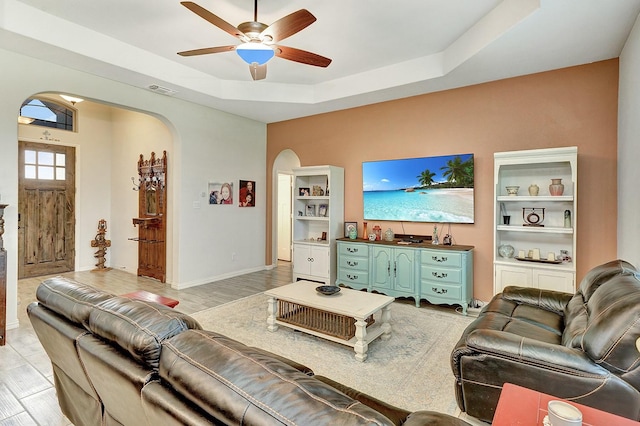 living room featuring ceiling fan and a tray ceiling