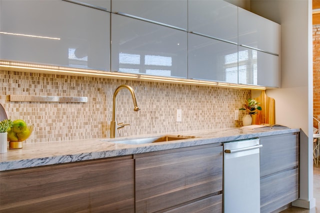 kitchen with sink, decorative backsplash, and light stone counters