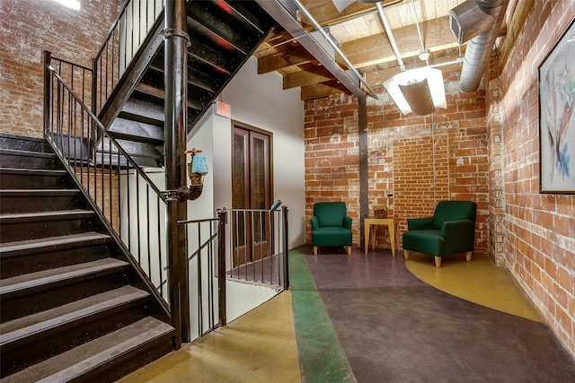 interior space with brick wall, a high ceiling, and concrete flooring