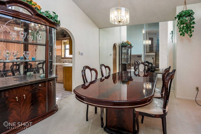 dining room featuring light carpet, sink, a textured ceiling, and an inviting chandelier