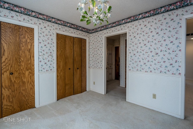 unfurnished bedroom featuring light colored carpet, a textured ceiling, and a closet