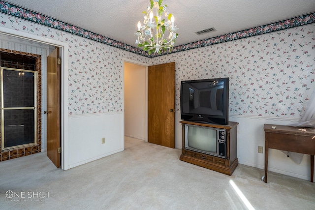 unfurnished living room featuring light colored carpet, a chandelier, and a textured ceiling