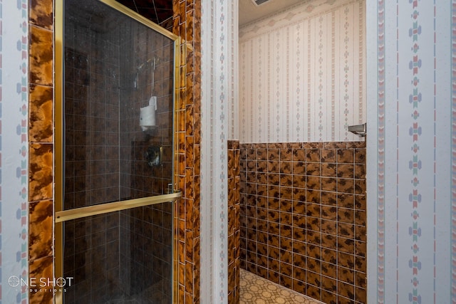 bathroom with a shower with door and tile walls