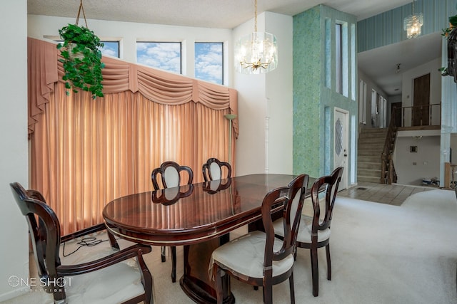 carpeted dining space with a chandelier and a textured ceiling