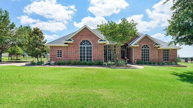 ranch-style home featuring brick siding, a front yard, and a shingled roof