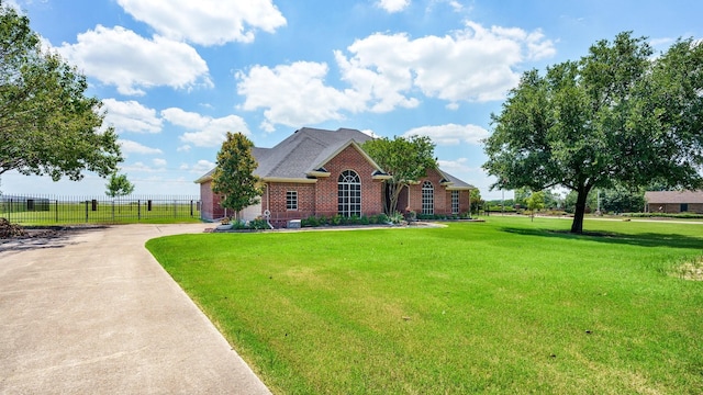 view of front of property with brick siding, concrete driveway, a front lawn, and fence