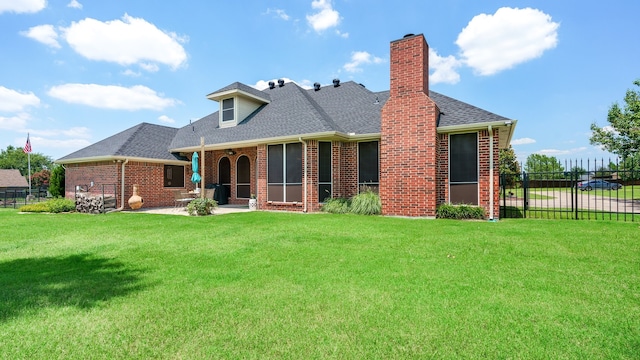 back of house featuring a lawn, a patio area, and a sunroom