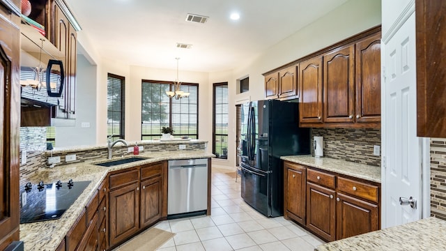 kitchen featuring black appliances, backsplash, light stone countertops, pendant lighting, and sink