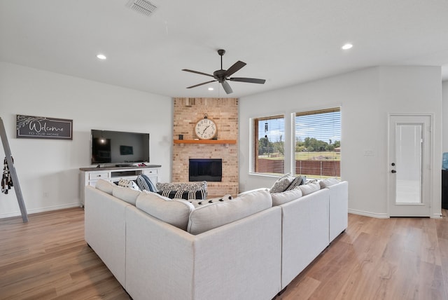 living room featuring a large fireplace, ceiling fan, and light hardwood / wood-style floors