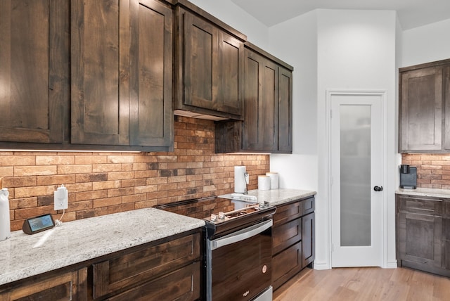 kitchen featuring backsplash, stainless steel stove, light hardwood / wood-style flooring, light stone countertops, and dark brown cabinets