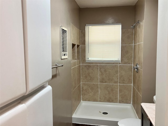 bathroom with tiled shower, vanity, and toilet