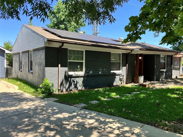 view of front of property featuring a front lawn and solar panels