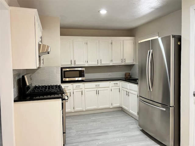 kitchen featuring light wood-type flooring, range hood, white cabinets, and appliances with stainless steel finishes