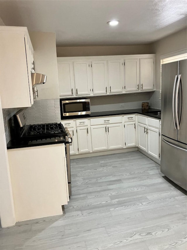 kitchen with white cabinetry, stainless steel appliances, range hood, and light wood-type flooring