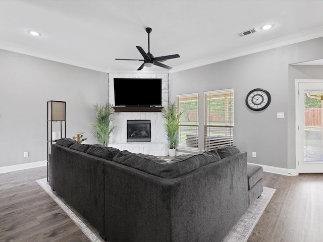 living room with crown molding, ceiling fan, dark hardwood / wood-style flooring, and a fireplace