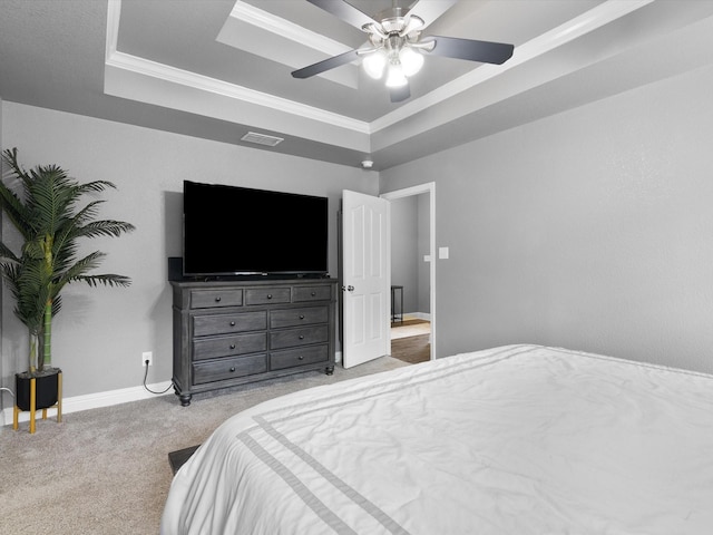 bedroom with ceiling fan, crown molding, light carpet, and a tray ceiling