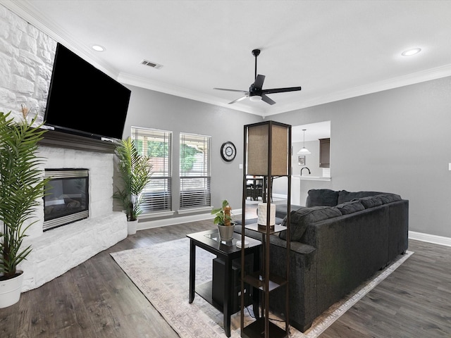 living room with ceiling fan, a fireplace, dark hardwood / wood-style floors, and ornamental molding