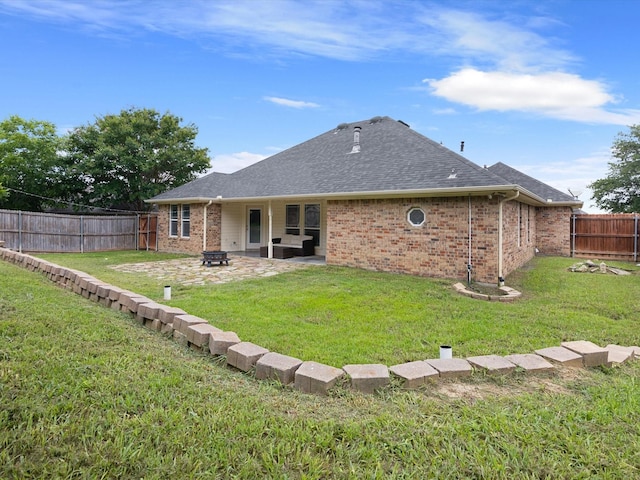 rear view of property with a lawn, a fire pit, and a patio